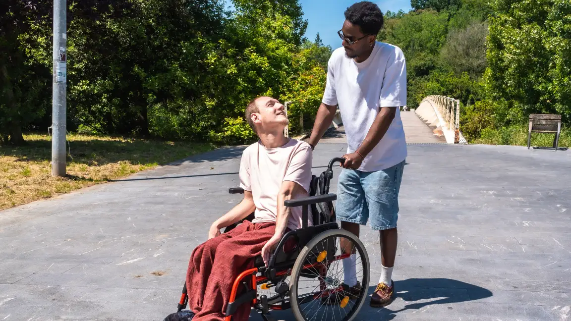Disabled man in wheelchair laughing with support worker