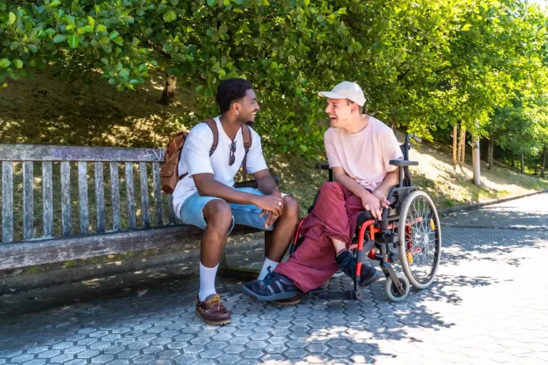Disabled man in wheelchair laughing with friend